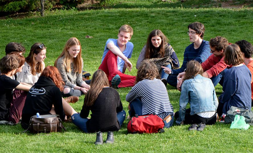 Ungdomar sitter i en ring på en gräsmatta