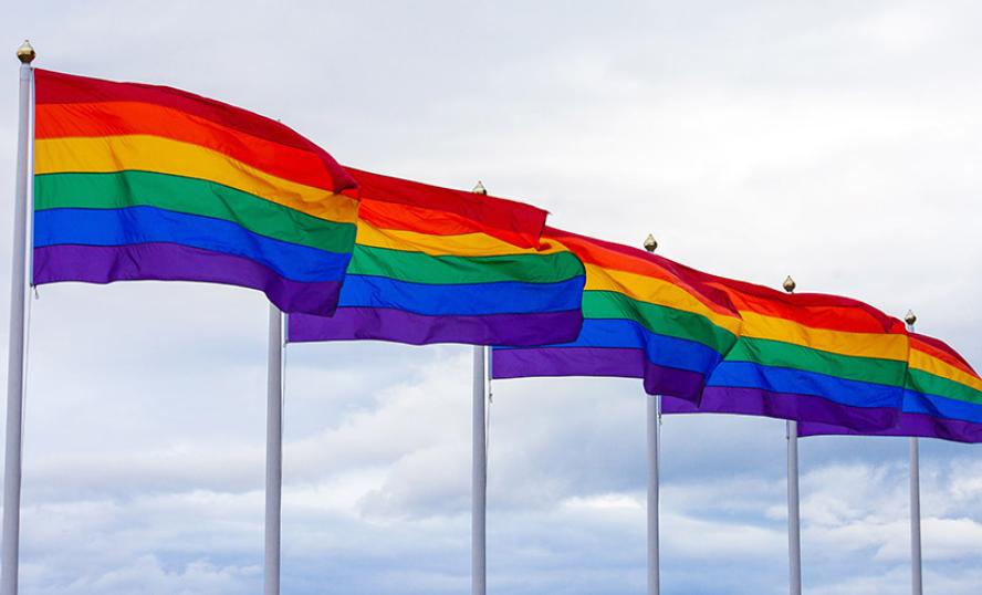 6 flaggstänger med regnbågsflaggan vajande i vinden