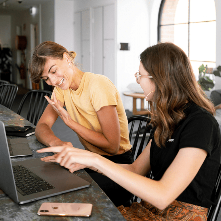 Två kvinnor som sitter och pratar framför en dator.