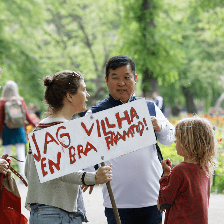 Två vuxna och ett barn med en demonstrationsskylt som säger jag vill ha en bra framtid.